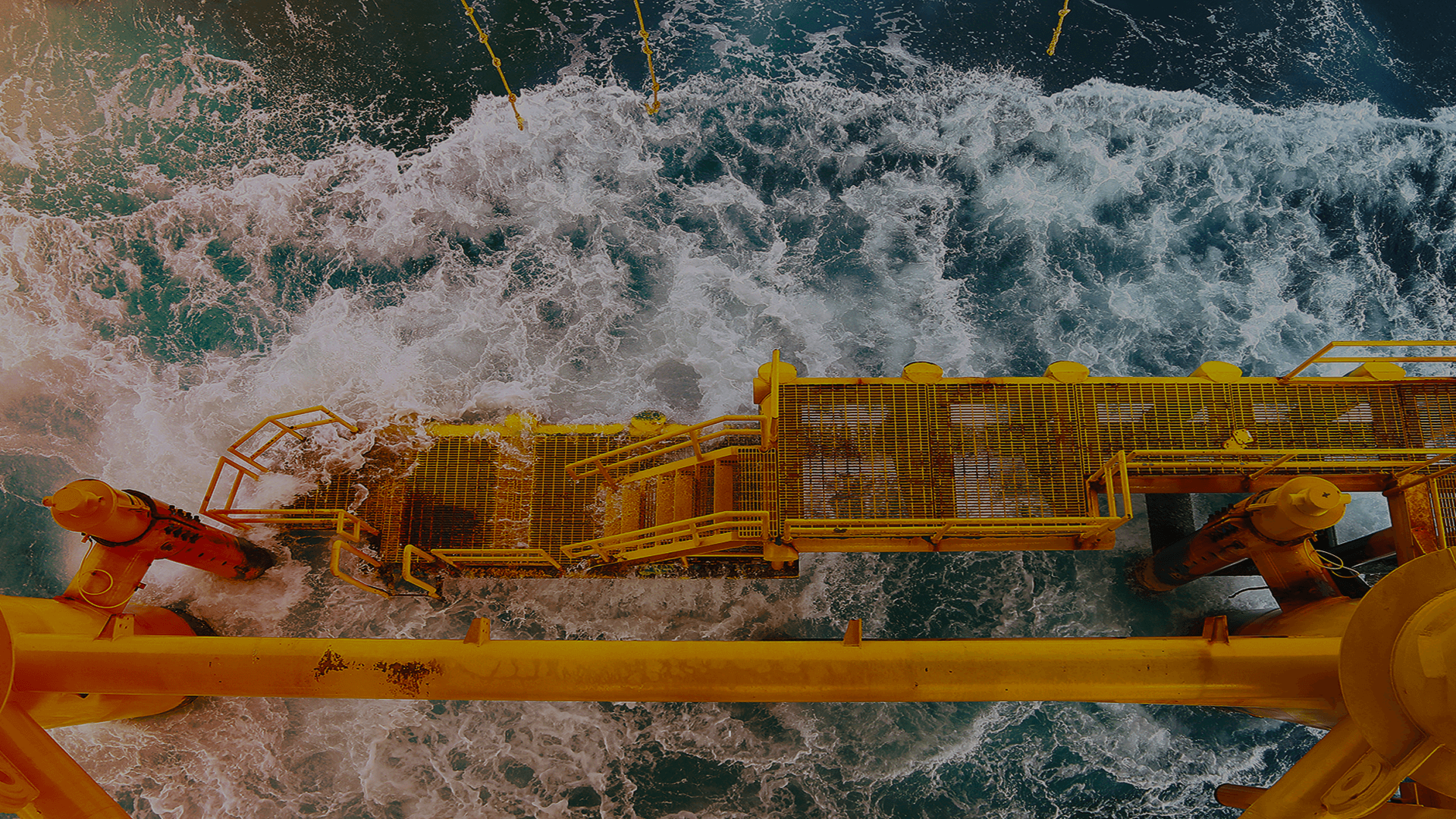 Offshore yellow metal platform with grated walkways over turbulent ocean waters. Waves crash against the structure, highlighting marine engineering for energy infrastructure. TEXO Engineering.